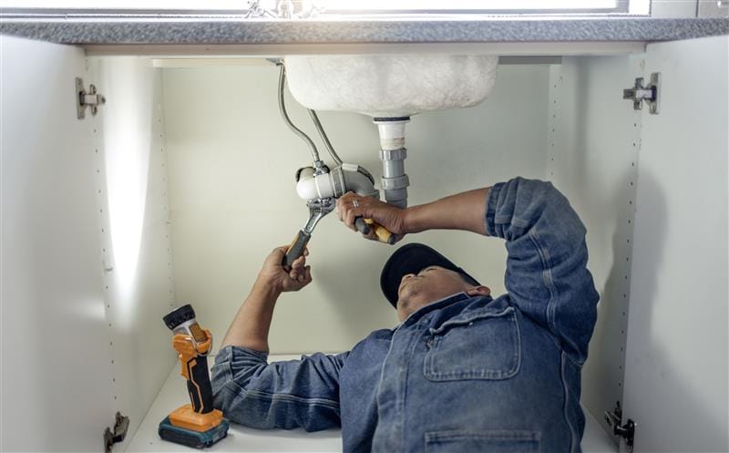 Plumber repairing pipes beneath a bathroom sink in Cartersville