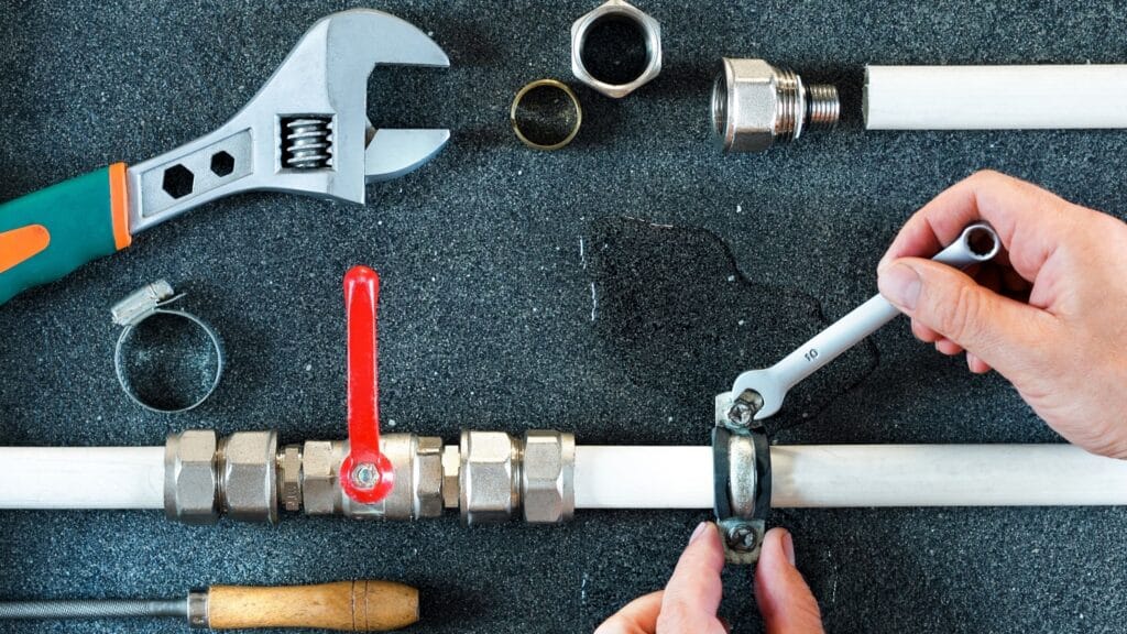 Plumber repairing a pipe valve with an adjustable wrench in Cartersville