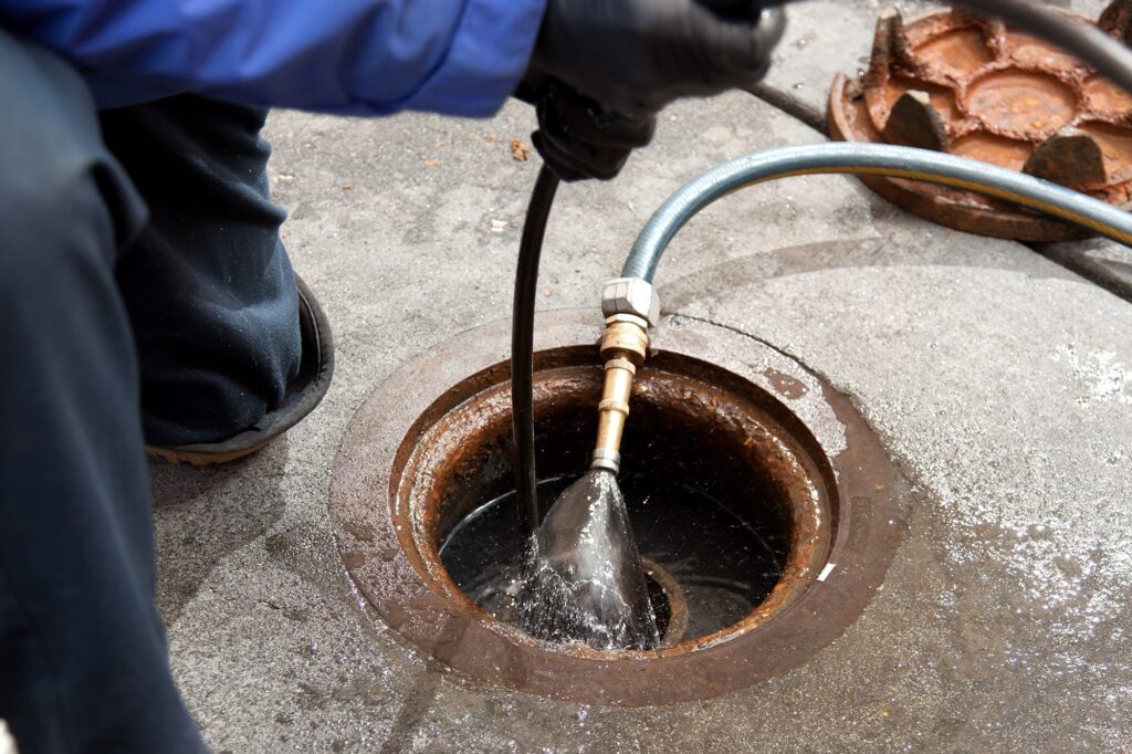 Plumber hydro jetting a sewer line through a manhole in Cartersville