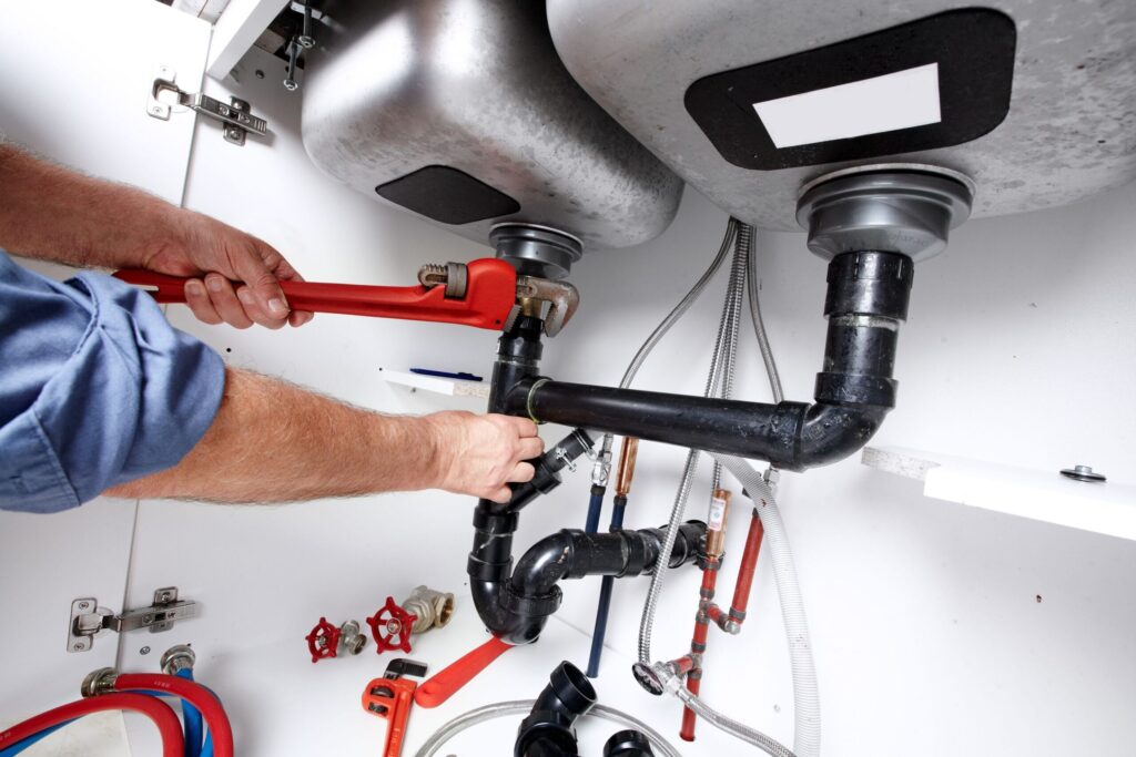 Plumber repairing drain pipes beneath a kitchen sink in Cartersville