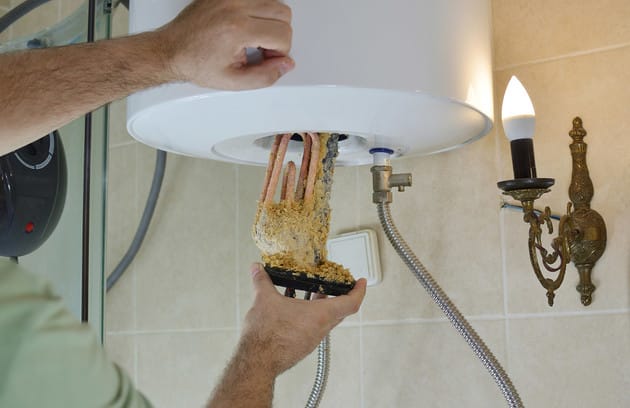 Technician removing mineral buildup from a water heater in Cartersville